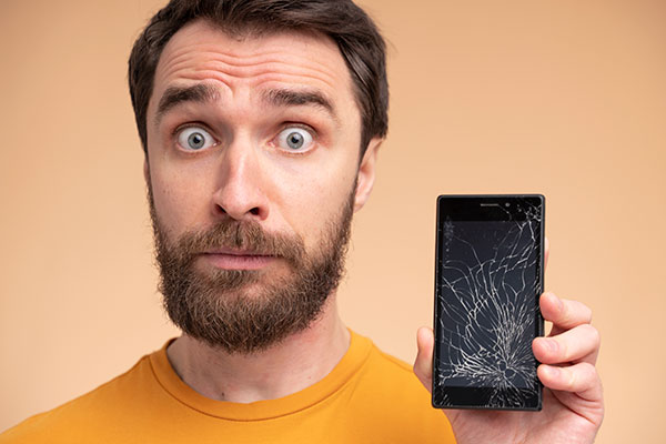 portrait-shocked-young-man-showing-his-broken-smartphone